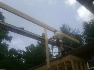 Carpenter setting a ridge beam over a new addition frame — Ice Dam Removal by Roofing Brothers in Newport News