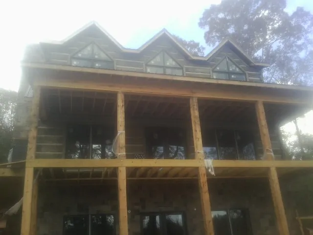 Dormers and porch framing on a large log home under construction — Roof Coating work by our crew in Newport News