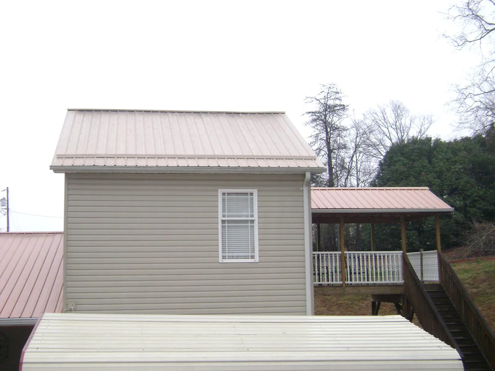Tan metal roofs on a two story addition and attached porch, from a Roof Replacement job in Newport News