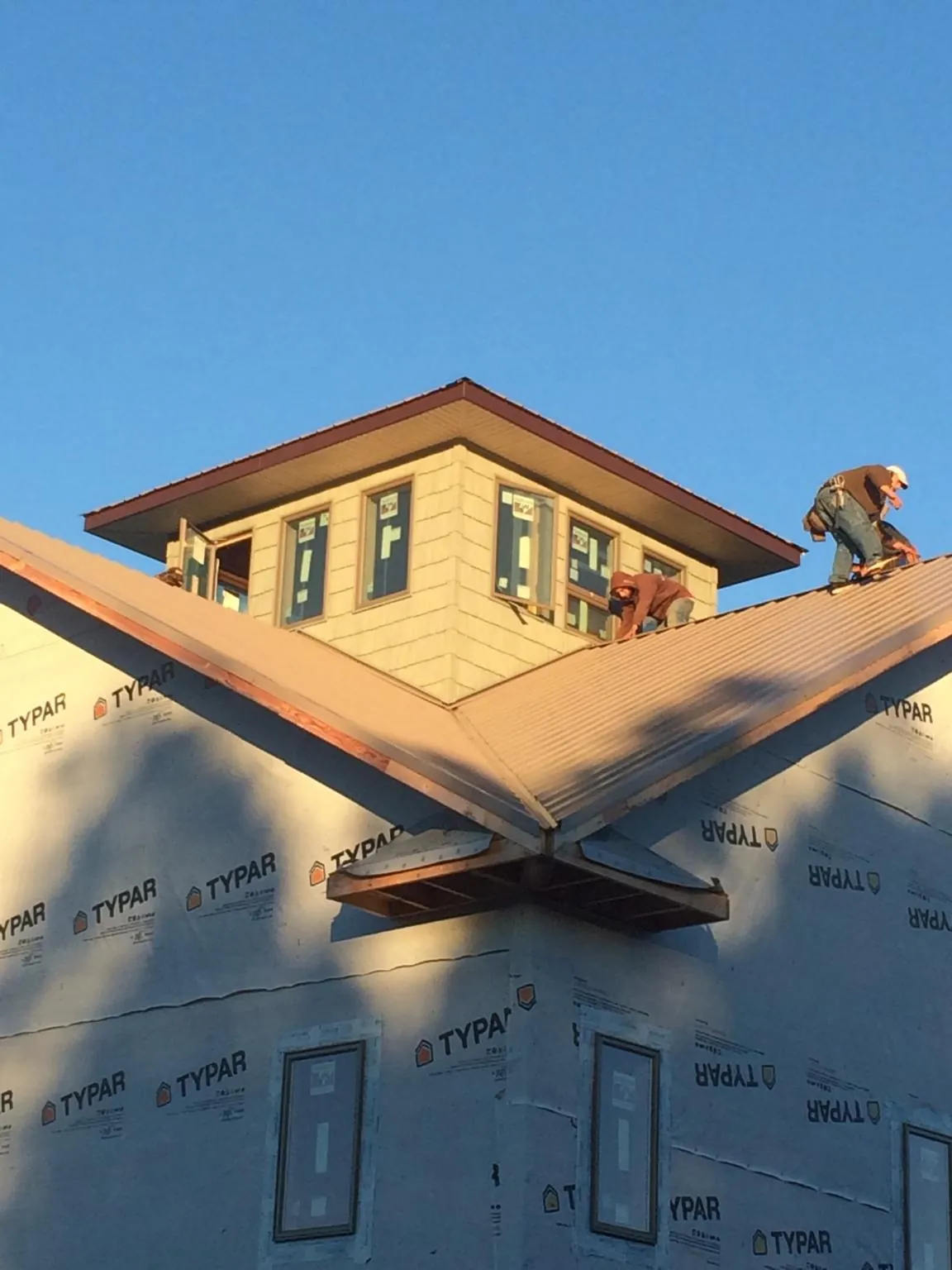 Roofers working around a rooftop cupola on a new metal roof at sunset — Roof Waterproofing in Newport News by Roofing Brothers